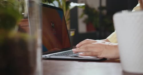 Closeup of Flower Shop Worker Using Laptop to Control Growth of Plants in
