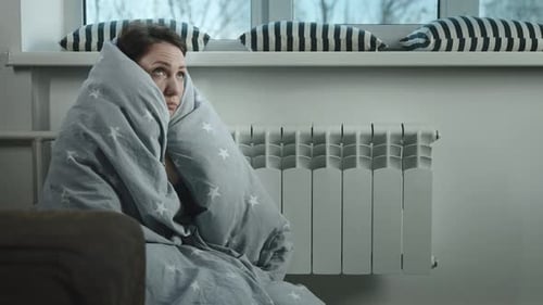 Woman Wrapped in Blanket Sitting by Radiator