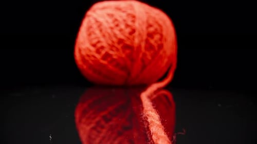 A ball of red woolen threads on black glass.. Dolly slider extreme close-up. Laowa Probe