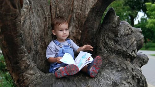 Cute lifestyle kid in garden having fun. Little boy in park sitting.