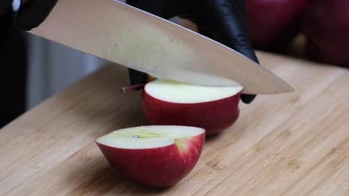Cuts an apple in half with a knife
