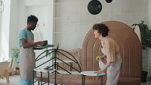 Two Diverse Cafe Workers Cleaning Tables and Taking Away Plates