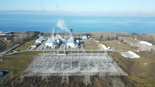 Eine Luftaufnahme einer Kamera, die von einer Elektrostation mit Kaminen zurückfliegt