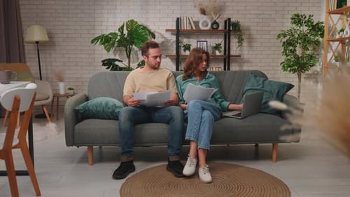 Couple Shopping Online Using Laptop on Comfortable Sofa