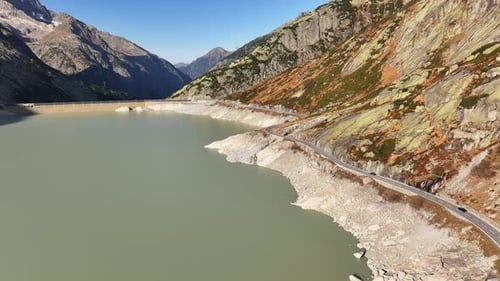 Grimsel water reservoir and mountain pass road on a sunny day with scenic views from above