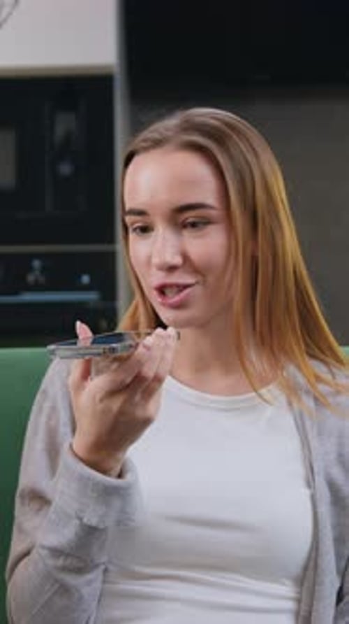 Smiling woman uses phone, sending a voice message
