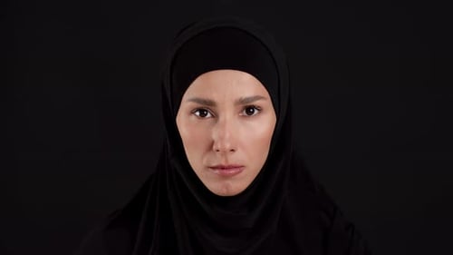 Woman Wearing a Black Headscarf Against Black Backdrop