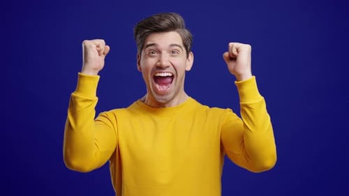 Excited man cheering with his fists on blue background