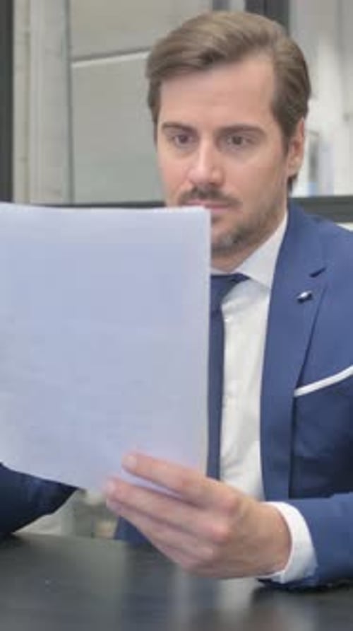 Man in Suit Reads Document with Positive Reaction