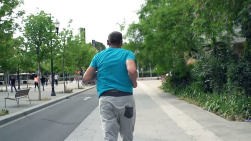 Young man jogging for fitness and training in the city on a bright day