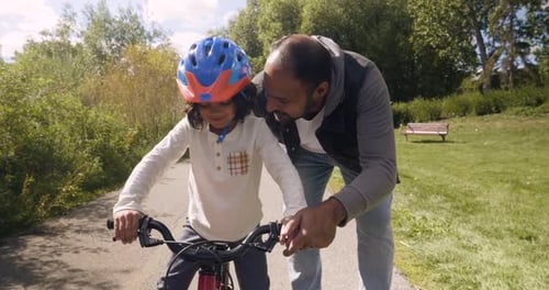 Father Teaching Daughter How to Ride Bicycle in Sunny Park 4044 Years