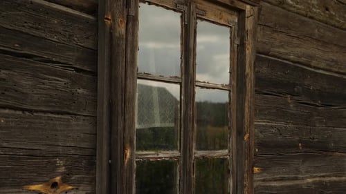 Altes und verwittertes Holzfenster an der Seite einer rustikalen Hütte Das Holz ist verdunkelt und gealtert mit