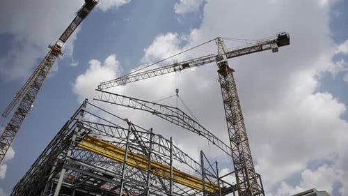 En lo alto, una grúa alta actúa como centinela en una obra de construcción, emblemática de la ambición humana y