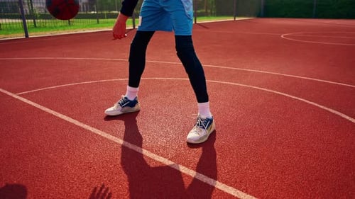 Ein großer Basketballspieler mit dem Ball zeigt seine Dribbling-Fähigkeiten beim Training auf dem Platz