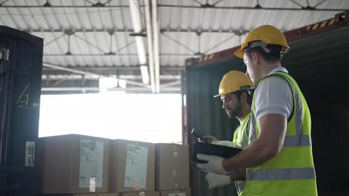 Blue collar workers are working at warehouse.