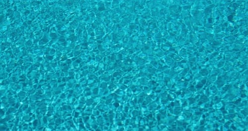 Crystal Clear Water in a Swimming Pool with Sunlight and Wind Creating Shimmering Ripples