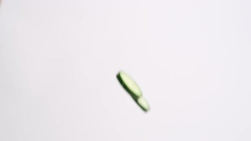 Cucumber Slices Falling on a White Background