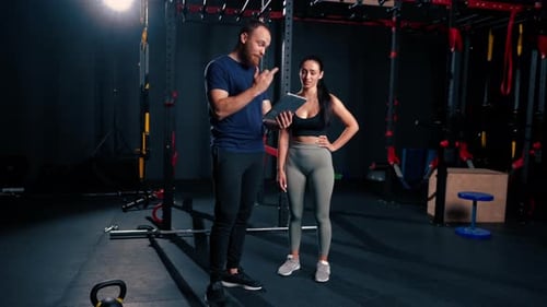 Trainer Explains Workout on Tablet in Gym