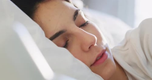 Authentic close up shot of an young brunette woman is sleeping peacefully wrapped in warm duvet bl