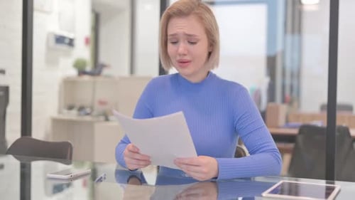Sad Woman Reads Document at Office Table