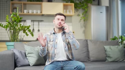 Young Man Talking on Phone While Sitting on Couch