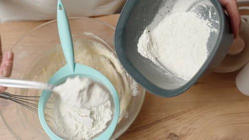 Hands Sifting Flour into Bowl of Cake Batter