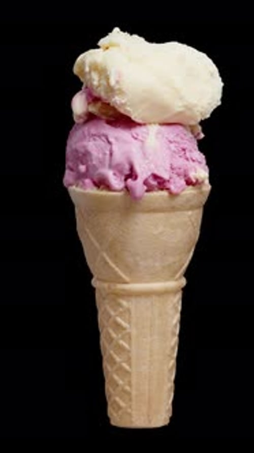 Vídeo vertical. Uma casquinha de waffle com duas bolas de sorvete, uma rosa e outra de cor creme
, gira