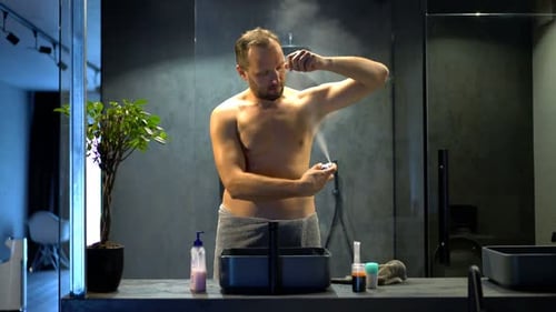 Man Applying Deodorant Spray in Bathroom