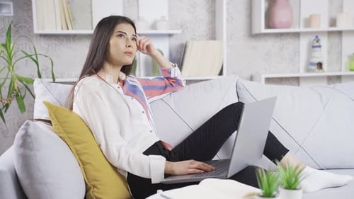 Young Woman Works on Laptop Relaxing on Sofa