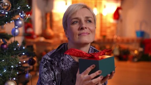 Woman with Gift Near Glowing Christmas Tree