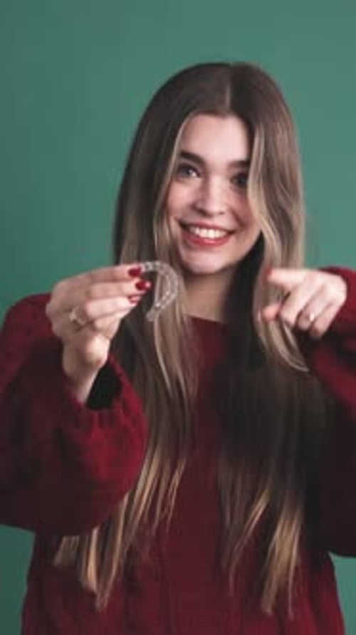 Mujer joven que muestra un soporte dental transparente