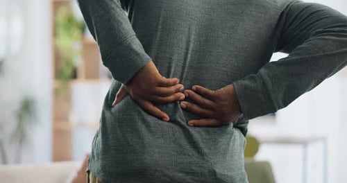 Back pain, hands and man in house with joint inflammation, crisis or anatomy risk closeup