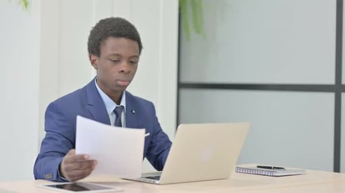 Young Adult Reviews Documents in Office Setting