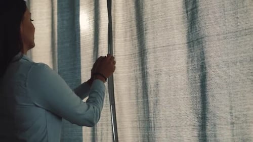 Woman Opens Curtains on Bright Sunny Morning