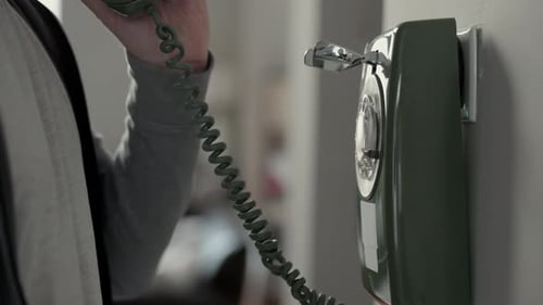 A Person Lifts the Receiver of a Vintage Wallmounted Rotary Telephone Classic Communication Retro