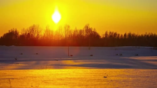 Time-lapse day to night of setting sun in yellow sky over snowy landscape at sunset. Space for copy