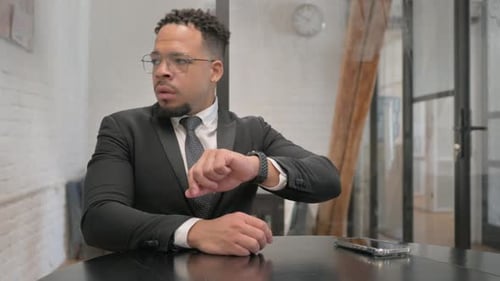 Businessman Checks Smartwatch at Table Indoors