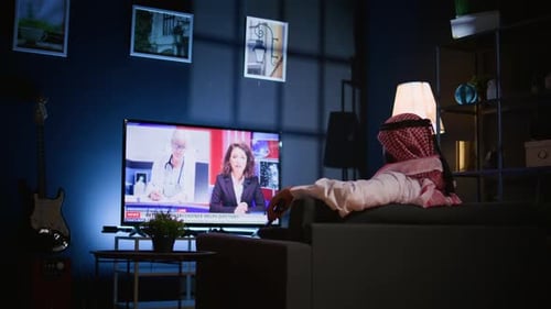 Man Lounged on Sofa Watching News