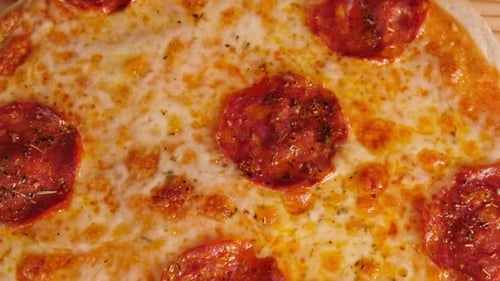 Close Up View Of A Freshly Baked Pizza With Melted Cheese On A Wooden Base