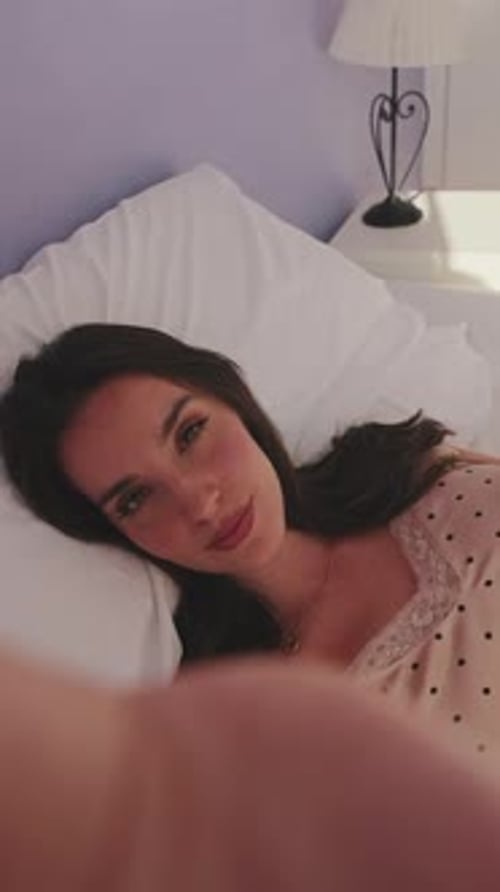 Close up, morning selfie of young beautiful woman lying in bed. Top view