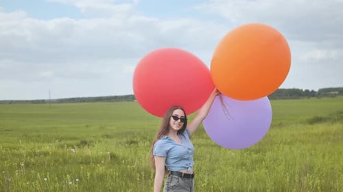 Happy Girl with Big Multicolored Balloons Posing on the Field