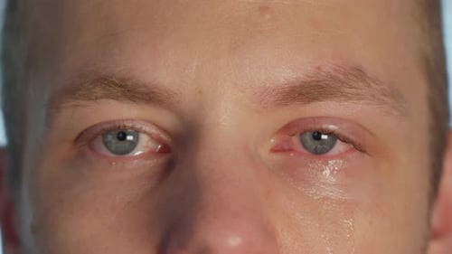 Caucasian male looking at camera, crying. Close up on eyes, handheld, 60fps
