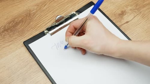 Close up of a hand writing “my business” with a blue pen on white paper clipped to a clipboard