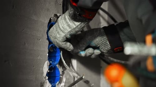 Electrician Installing Wiring in Wall Outlet Box