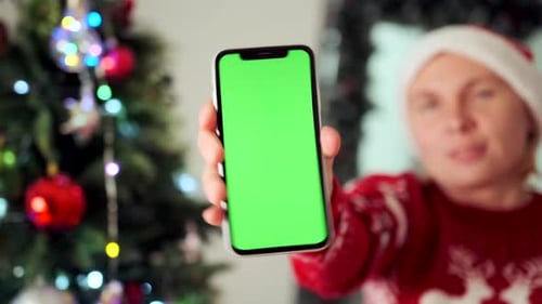 Woman's hand shows phone with green screen advertising New Year sale application