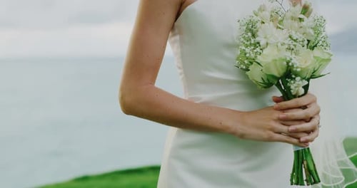Bride Holding Bouquet on Ocean Coastline