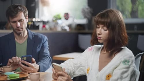 Friends are Sitting on Their Phones at a Meeting in a Cafe for Coffee