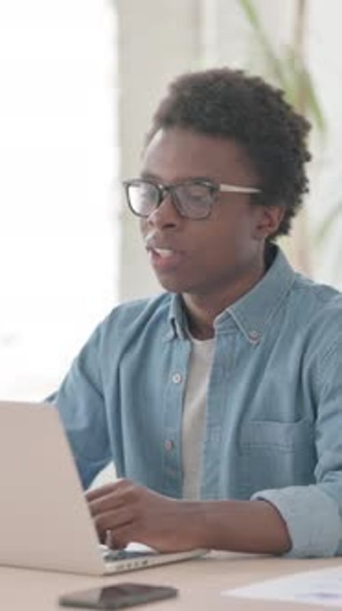 Young African Man Talking on Video Call on Laptop in Office, Vertical Video
