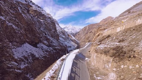 Snow-Covered Mountain Road Through Rocky Terrain Under a Clear Blue Sky