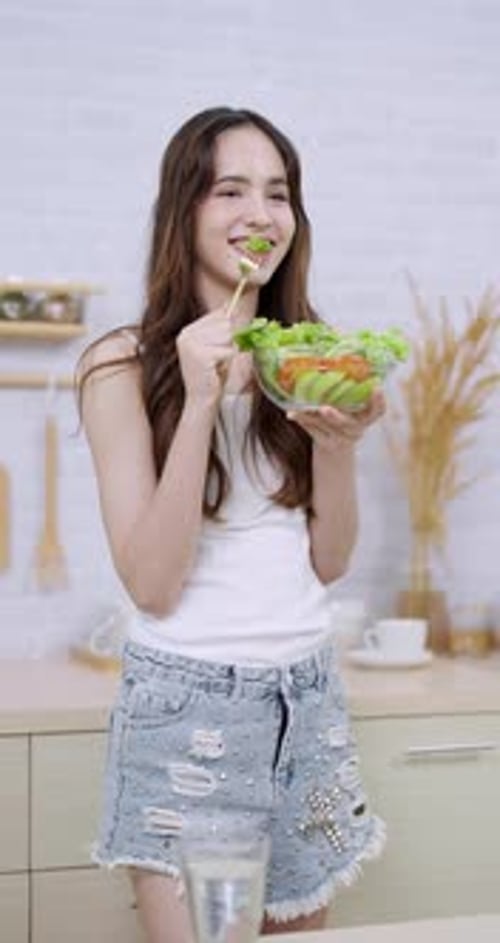Cheerful young woman enjoys eating a fresh salad